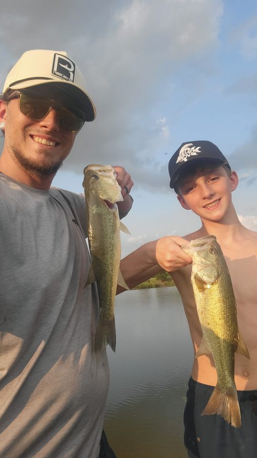 Customer holding a bass in a Reeled In hat