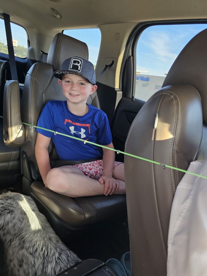 Kid in the truck with a rod, wearing a Reeled In hat