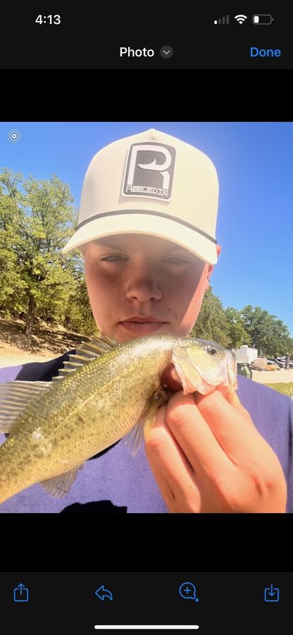 Young angler holding a bass in a Reeled In hat